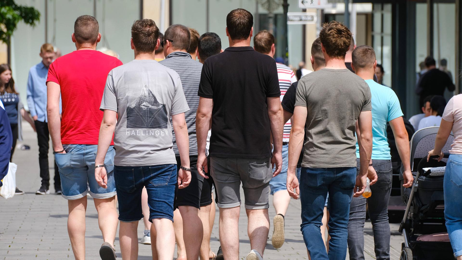Junge Männer laufen durch die Düsseldorfer Innenstadt (von hinten gesehen)