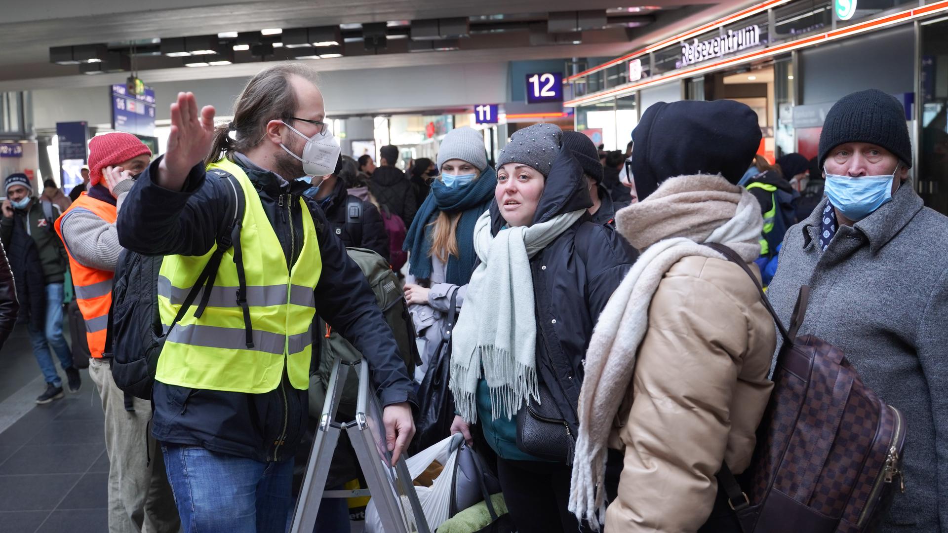 Der freiwillige Helfer Marcel, ein Ingenieur in Elternzeit, sagt am Berliner Hauptbahnhof gerade angekommenen Flüchtlingen, wie sie ins Landesamt für Flüchtlingsangelegenheiten (LAF) kommen oder wie sie einen Bahnfahrschein für die Weiterfahrt erhalten.