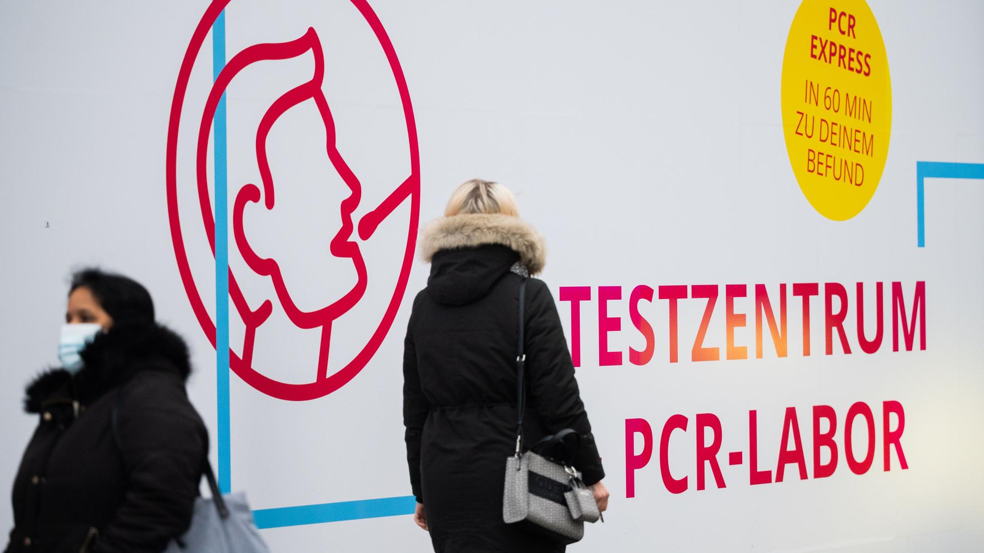 Passanten laufen an einem Corona-Testzentrum vorbei, das mit einem PCR-Express-Test wirbt Passanten laufen an einem Corona-Testzentrum vorbei, das mit einem PCR-Express-Test wirbt