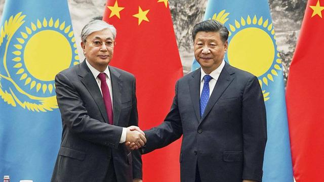 Der kasachische Präsident Kassym-Jomart Tokajew (links) steht neben dem chinesischen Präsidenten Xi Jinping (rechts). Im Hintergrund sind die Flaggen von Kasachstan und China zu sehen.