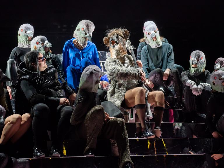 Bühnenszene aus der Operette "Die Rache der Fledermaus" am Thalia Theater. Björn Meyer sitzt mit Fledermausmaske in der Mitte, umrahmt von mehreren Darstellerinnen und Darstellern.
