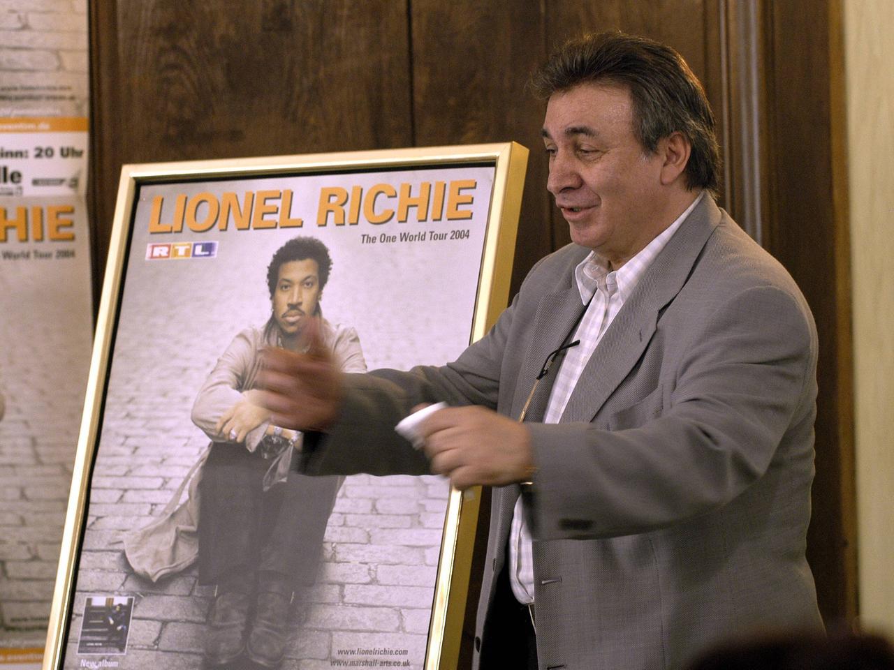 Marcel Avram hält ein Konzertplakat des Sängers Lionel Ritchie in die Kamera Marcel Avram hält ein Konzertplakat des Sängers Lionel Ritchie in die Kamera