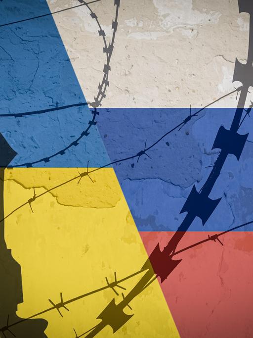 Schatten von Militärhelm, Maschinengewehr und Stacheldraht vor einer in den Farben der Ukraine und Russlands bemalten Wand