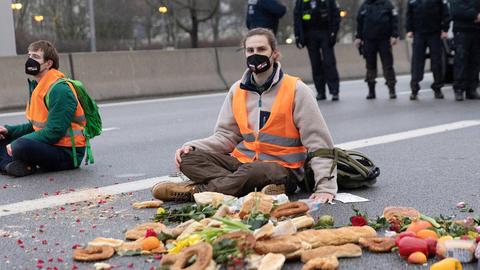 Klimaaktivisten bei einer Autobahnblockade, sie sitzen auf dem Aspalt und haben sich mit Sekundenkleber die Hände am Boden festgeklebt, 04.02.2022.