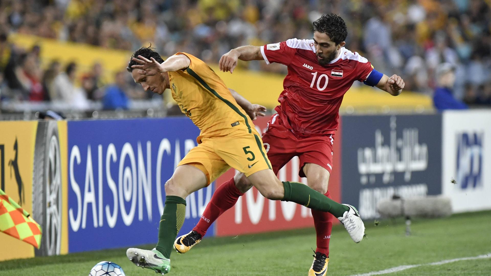 Der australische Mittelfeldspieler Mark Milligan greift den syrischen Nationalstürmer Firas al-Khatib während eines WM-Qualifiktationsspiels an Der australische Mittelfeldspieler Mark Milligan greift den syrischen Nationalstürmer Firas al-Khatib während eines WM-Qualifiktationsspiels an
