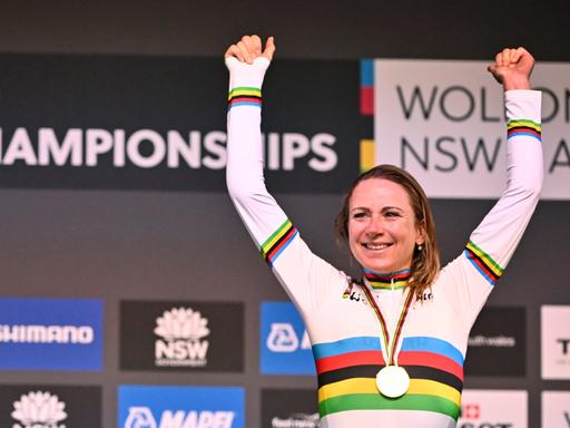Annemiek van Vleuten jubelt im Weltmeistertrikot mit Regenbogenstreifen auf dem Siegerpodest.