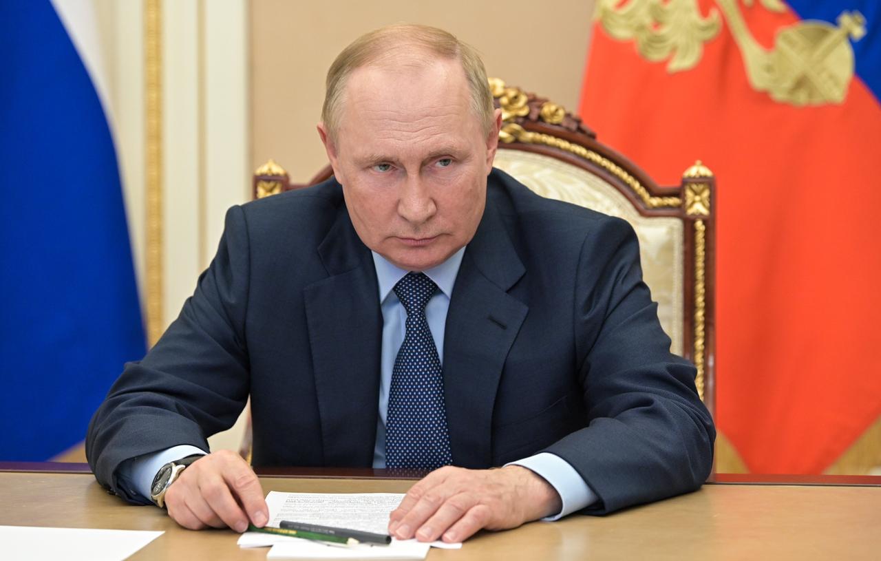 Wladimir Putin sitzt vor zwei Flaggen an einem Tisch. Wladimir Putin sitzt vor zwei Flaggen an einem Tisch.