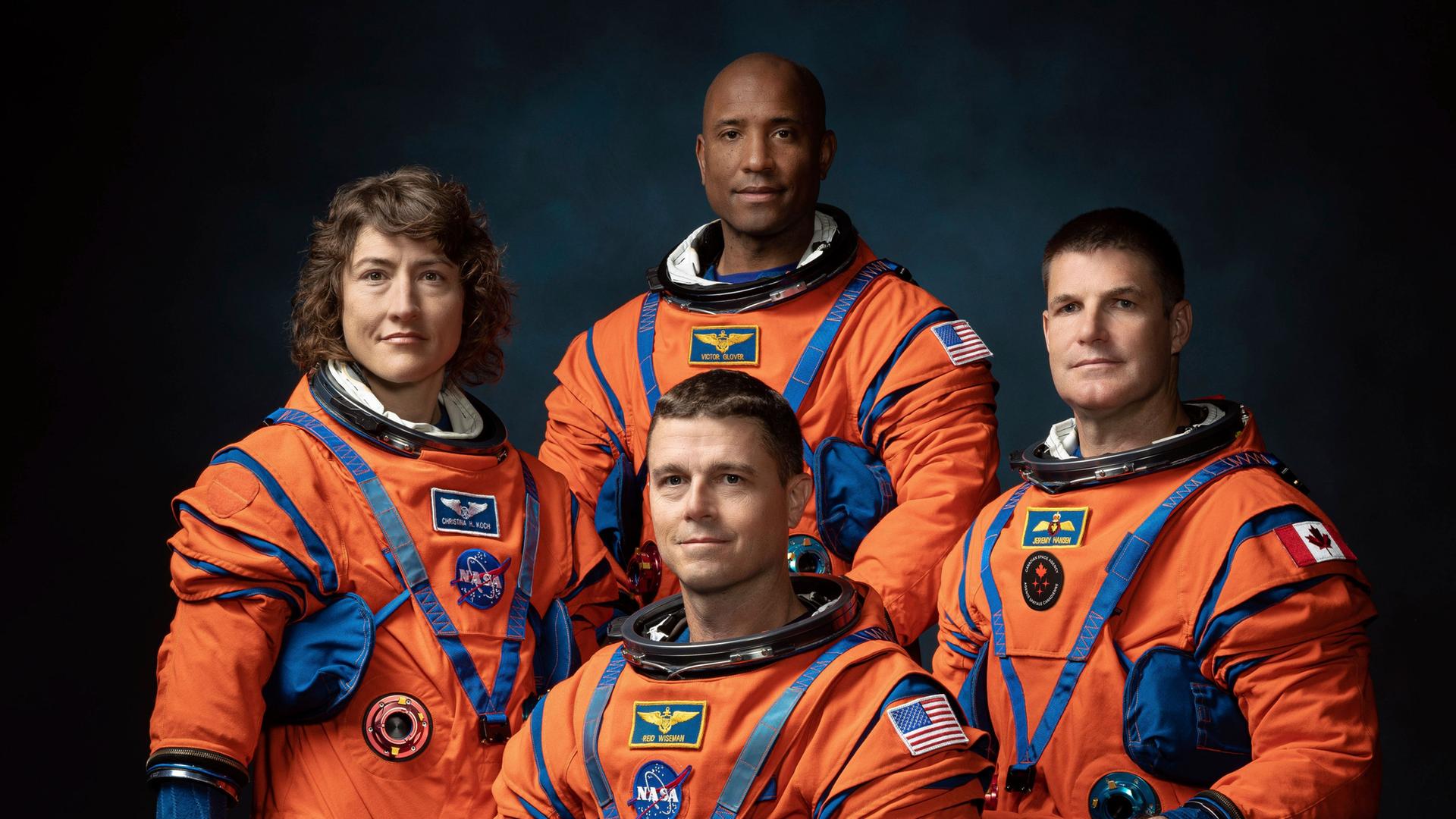 Das Foto zeigt die Mitglieder der Mond-Mission "Artemis II". Sie haben orangene Raum-Anzüge an.