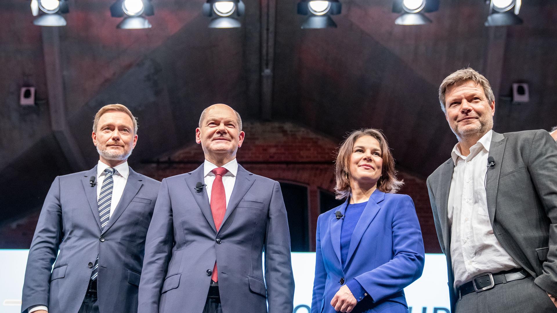 Christian Lindner, Olaf Scholz, Annalena Baerbock und Robert Habeck stehen bei einer Pressekonferenz auf einer Bühne. Im Hintergrund sind Scheinwerfer zu sehen. Christian Lindner, Olaf Scholz, Annalena Baerbock und Robert Habeck stehen bei einer Pressekonferenz auf einer Bühne. Im Hintergrund sind Scheinwerfer zu sehen.