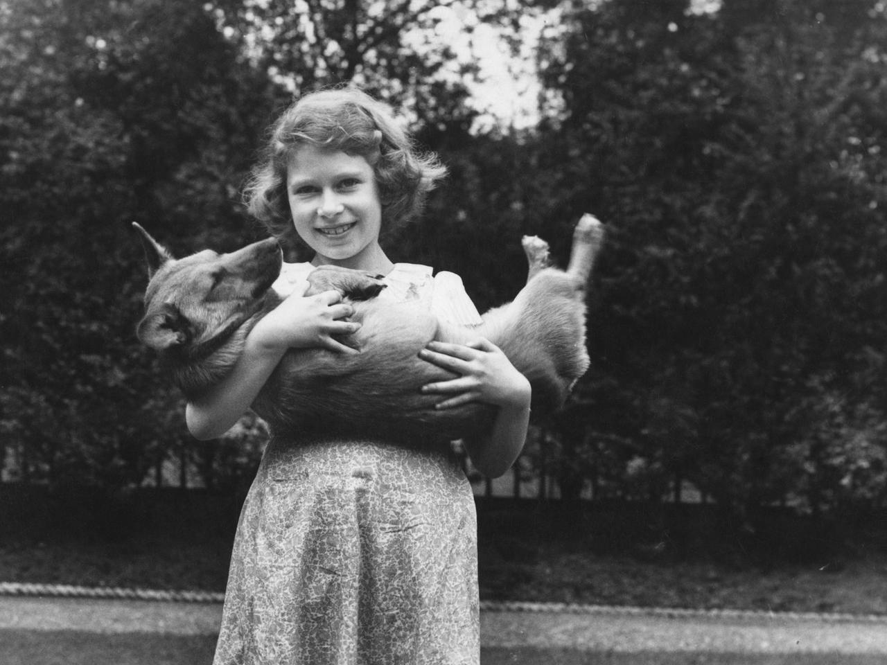 Prinzessin Elizabeth als junges Mädchen mit einem Corgi im Arm.