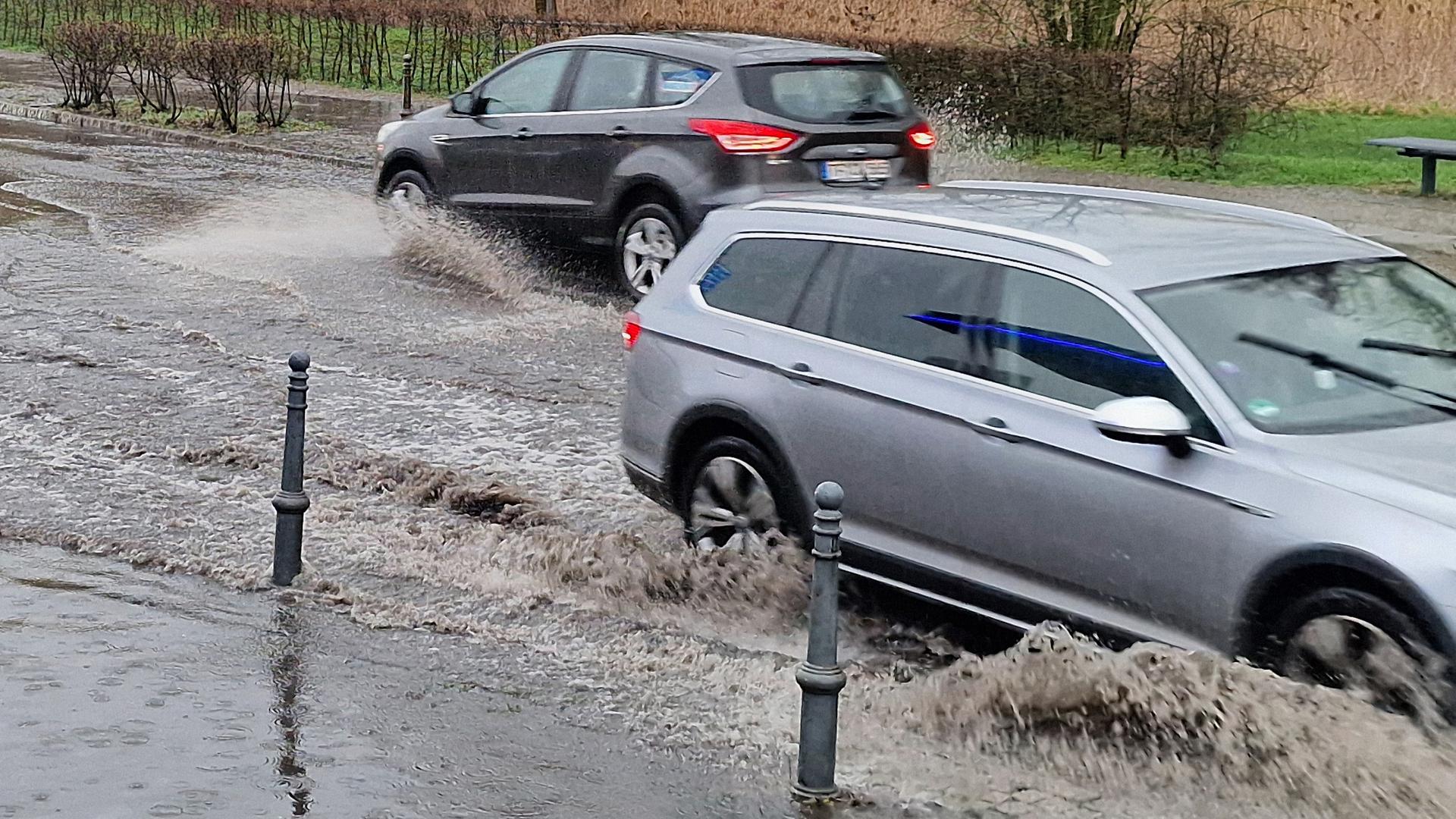 Autos fahren durch eine von Regen überflutete Straße. Autos fahren durch eine von Regen überflutete Straße.