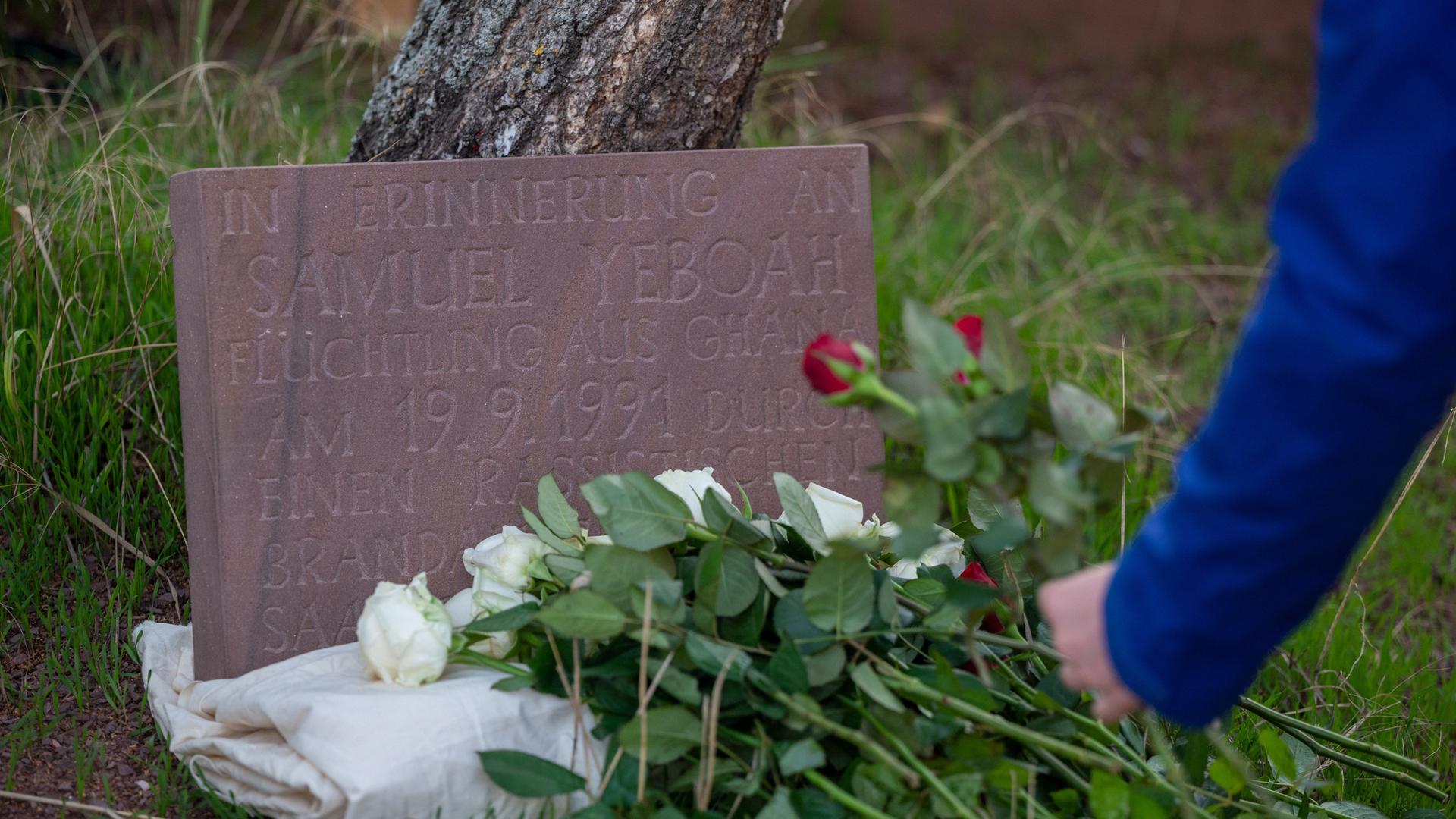 Eine Teilnehmerin der Gedenkkundgebung für den 1991 bei einem Brandanschlag getöteten ghanaischen Asylbewerber Samuel Yeboah legt an einem Gedenkstein Blumen ab Eine Teilnehmerin der Gedenkkundgebung für den 1991 bei einem Brandanschlag getöteten ghanaischen Asylbewerber Samuel Yeboah legt an einem Gedenkstein Blumen ab
