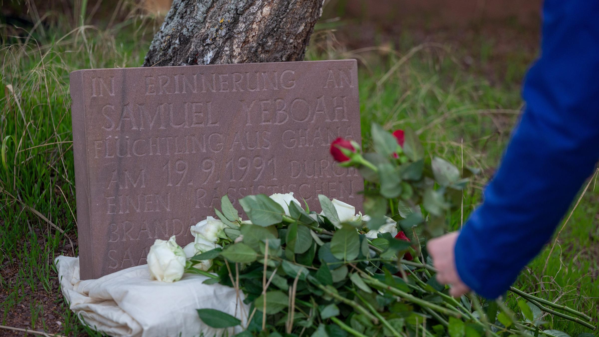 Eine Teilnehmerin der Gedenkkundgebung für den 1991 bei einem Brandanschlag getöteten ghanaischen Asylbewerber Samuel Yeboah legt an einem Gedenkstein Blumen ab