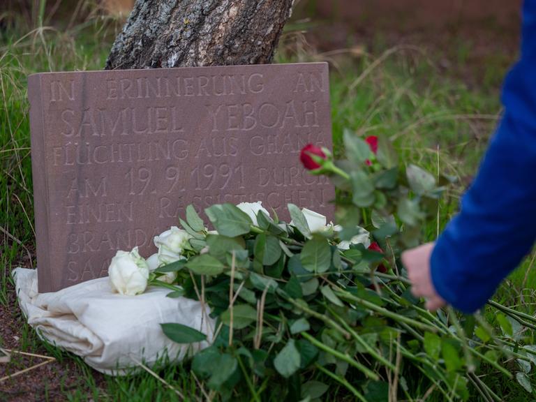 Eine Teilnehmerin der Gedenkkundgebung für den 1991 bei einem Brandanschlag getöteten ghanaischen Asylbewerber Samuel Yeboah legt an einem Gedenkstein Blumen ab