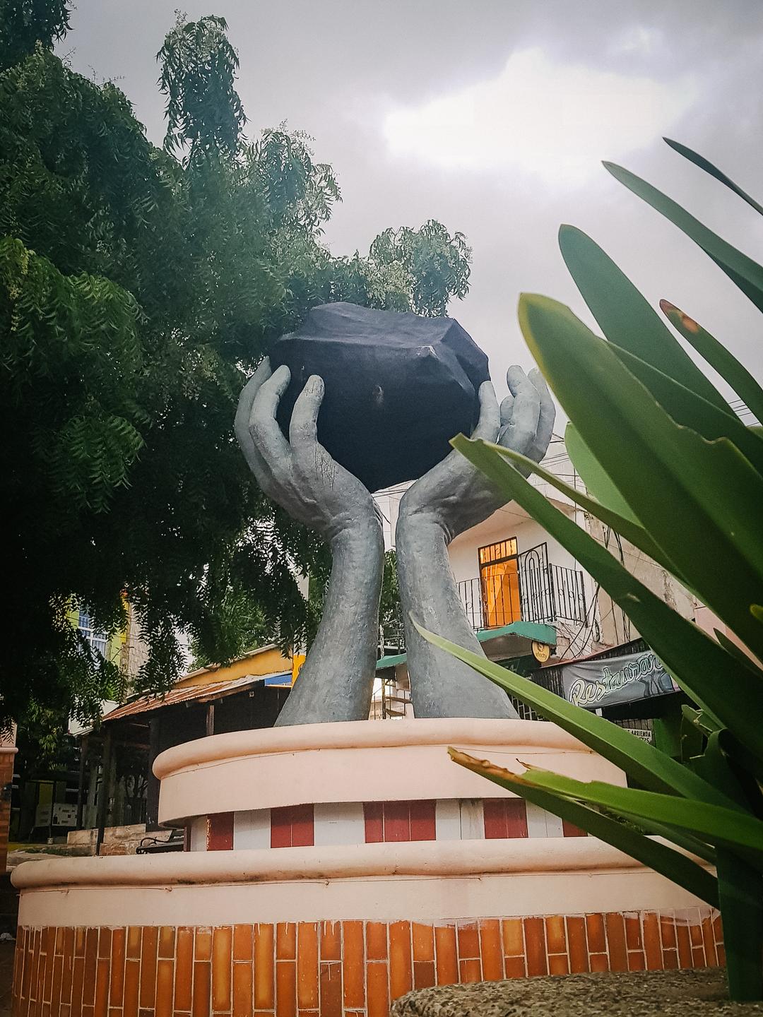Monument für die Kohleförderung in Albania: Zwei überdimensionale Hände halten einen als schwarzen Kohlebrocken angemalten Klotz in die Höhe. Monument für die Kohleförderung in Albania: Zwei überdimensionale Hände halten einen als schwarzen Kohlebrocken angemalten Klotz in die Höhe.