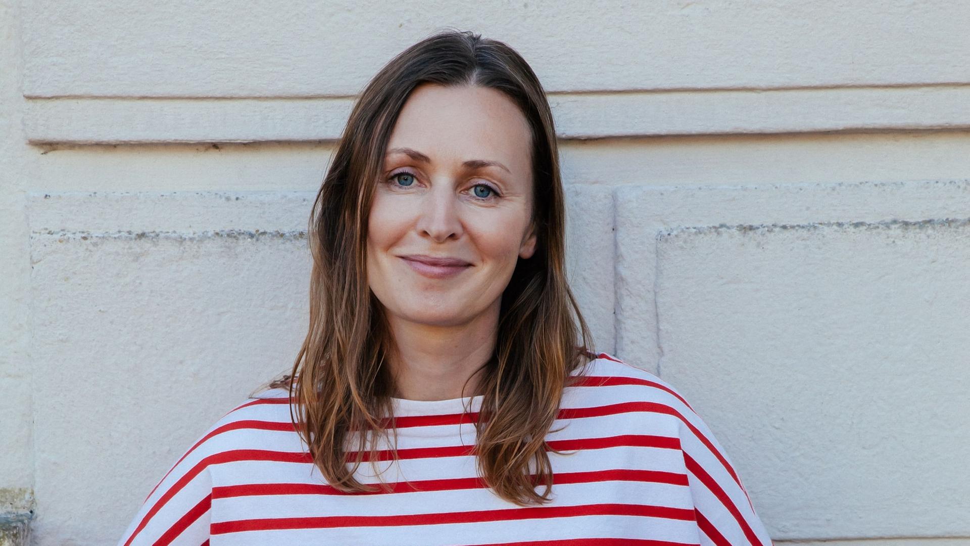 Nicole Zepter steht vor einer Wand und lächelt Nicole Zepter steht vor einer Wand und lächelt