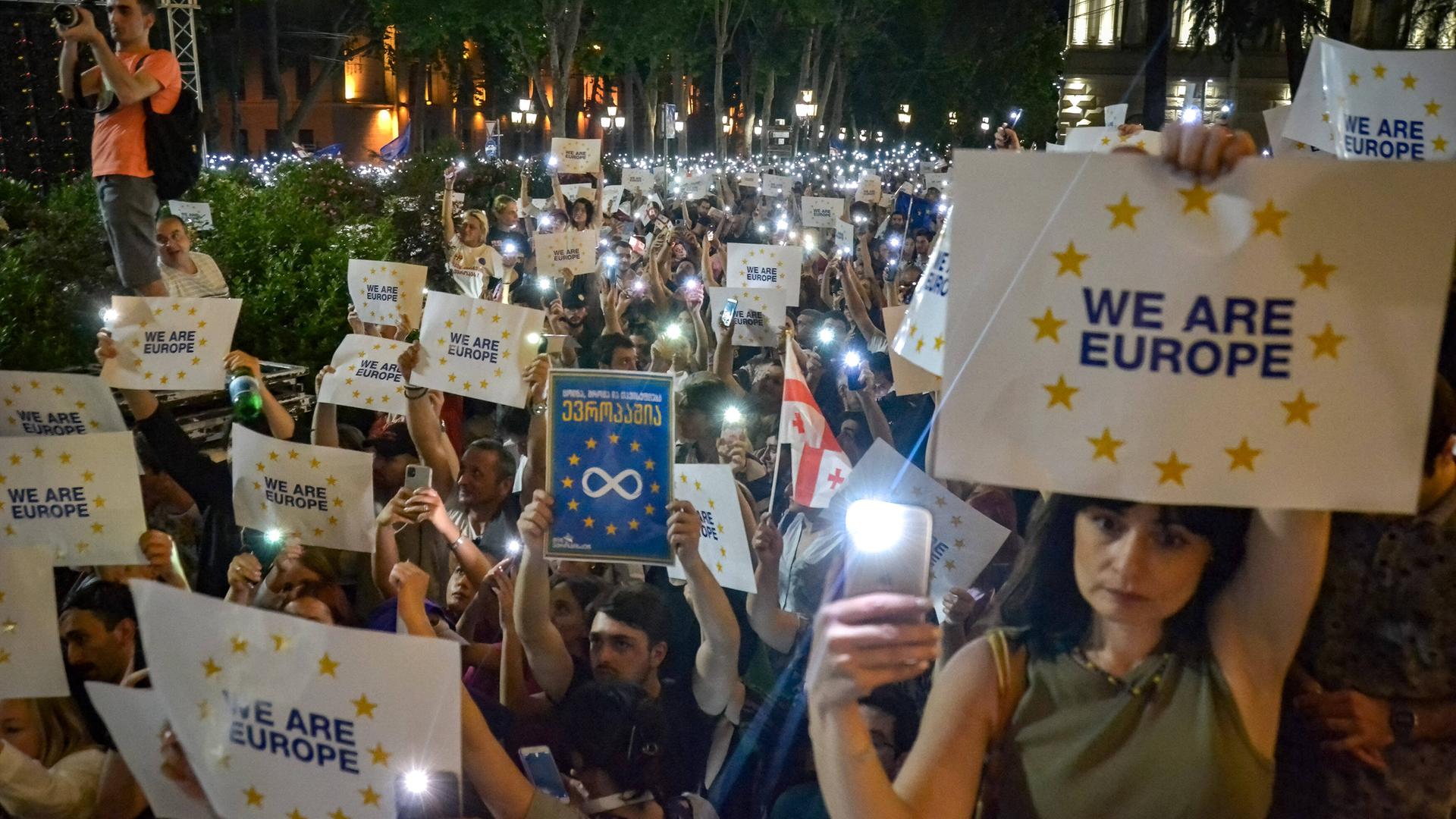 June 20, 2022, Tbilisi, Georgia: Pro EU protesters hold their smartphone with the flashlight on and placards written on