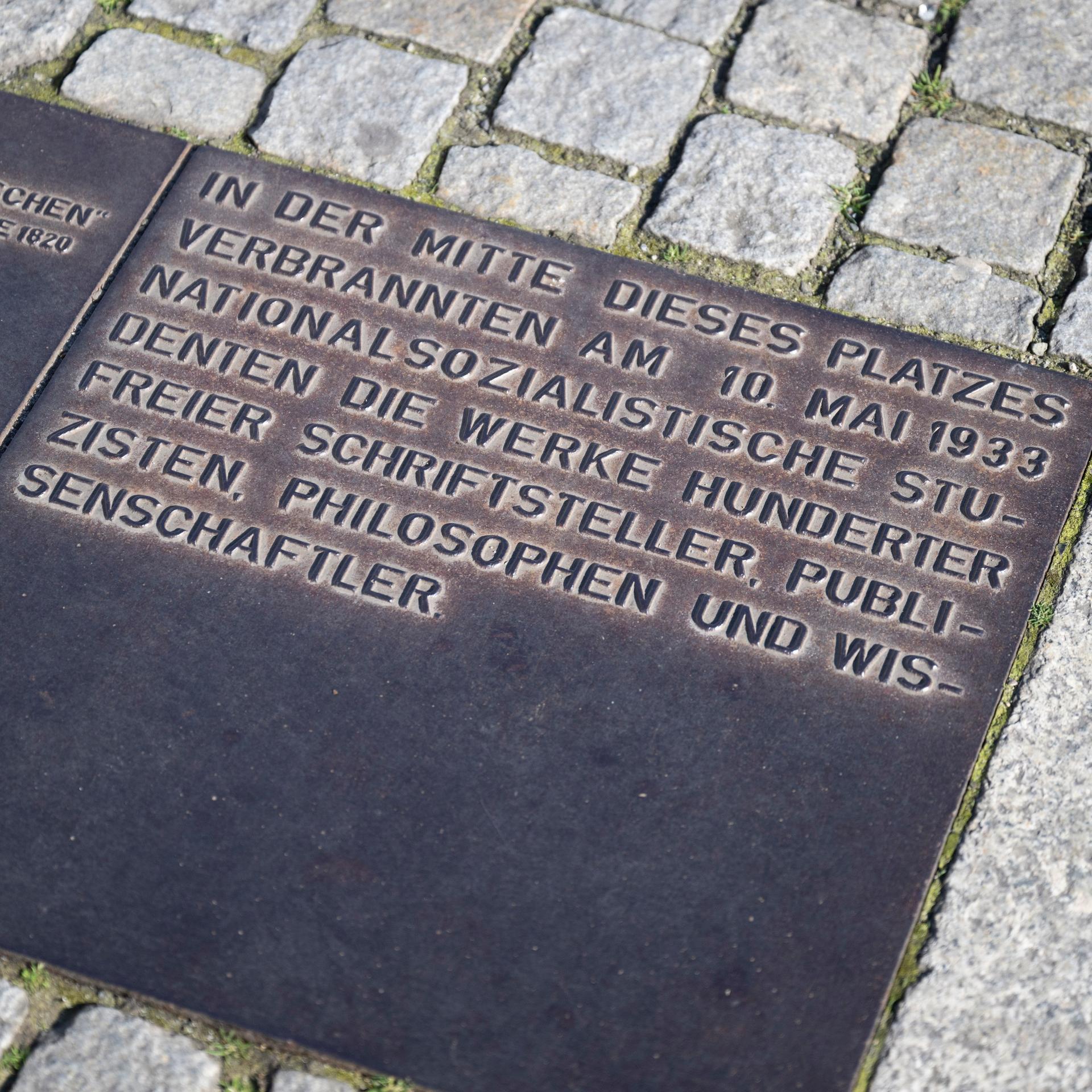 Eine Metallplakette erinnert an die Bücherverbrennung vom 10. Mai 1933 und würdigt die von den Nationalsozialisten verfolgten Schriftsteller, Wissenschaftler und Philosophen.