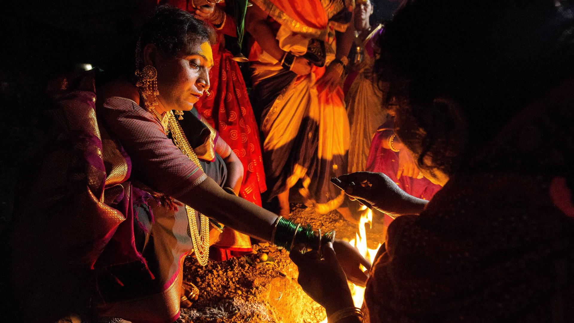 Eine Hijra in Indien bei einem religiösen Ritual an einem Feuer. Eine Hijra in Indien bei einem religiösen Ritual an einem Feuer.