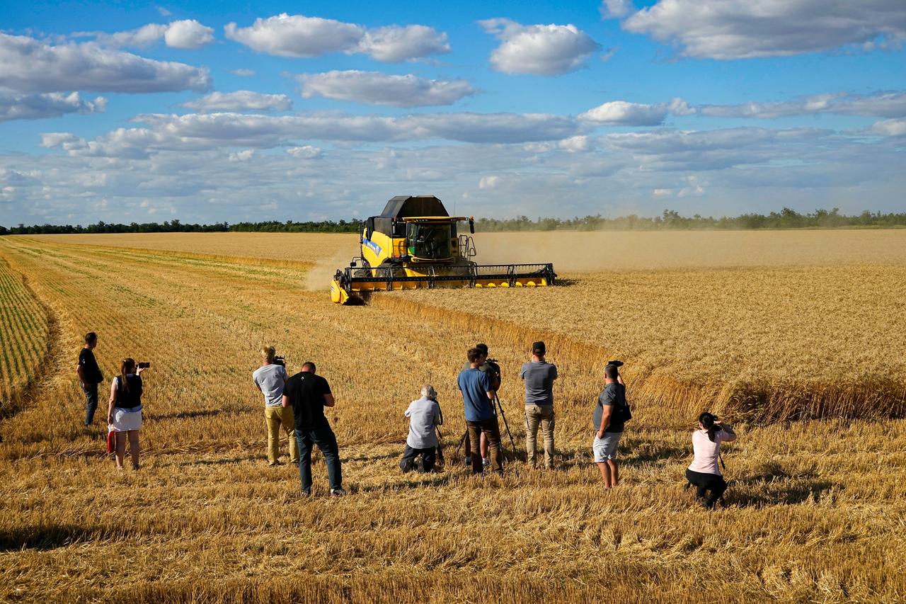 Journalisten fotografieren einen Mähdrescher auf einem Kornfeld in der Ukraine Journalisten fotografieren einen Mähdrescher auf einem Kornfeld in der Ukraine