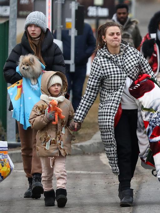 Geflüchtete ukrainische Frauen und ihre Kinder, die gerade über die Grenze nach Polen kommen.  