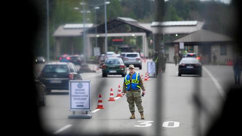 Sicherheitskontrolle bei der Zufahrt zur Airbase Ramstein - das Foto ist durch einen Zaun aufgenommen, der am Rand ins Bild ragt. 