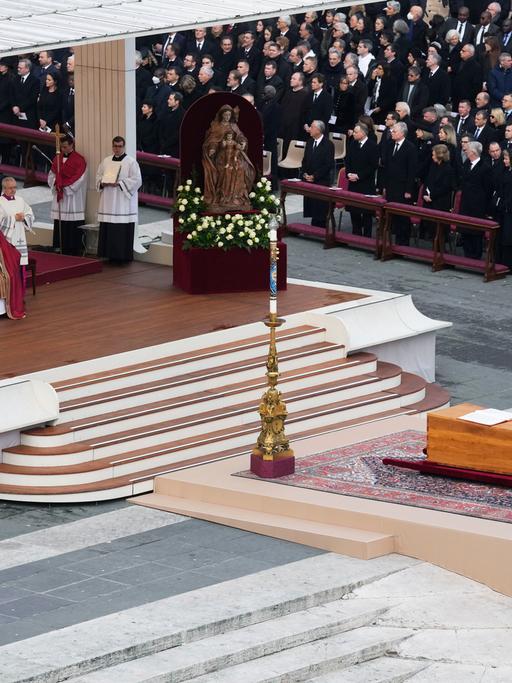 Ein bild von der Trauer-Feier: Man sieht einen Altar. Davor ist der Sarg von Papst Benedikt.