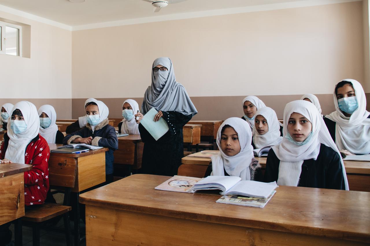 Schülerinnen mit Kopftuch sitzen an Pulten, eine Lehrerin mit Kopftuch steht im Klassenraum: die Safaa-Schule im Norden Kabuls, Afghanistan. Schülerinnen mit Kopftuch sitzen an Pulten, eine Lehrerin mit Kopftuch steht im Klassenraum: die Safaa-Schule im Norden Kabuls, Afghanistan.