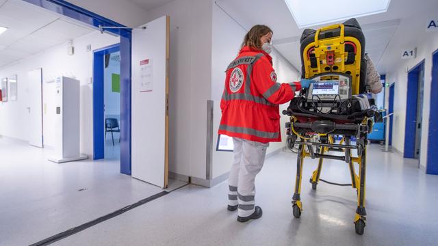 Eine Notfallsanitäterin des Deutschen Roten Kreuzes (DRK), schiebt eine Seniorin nach einem Schlaganfall auf einer Trage in die Notaufnahme eines Krankenhauses und wartet auf die Ãbergabe an die diensthabende Ãrztin