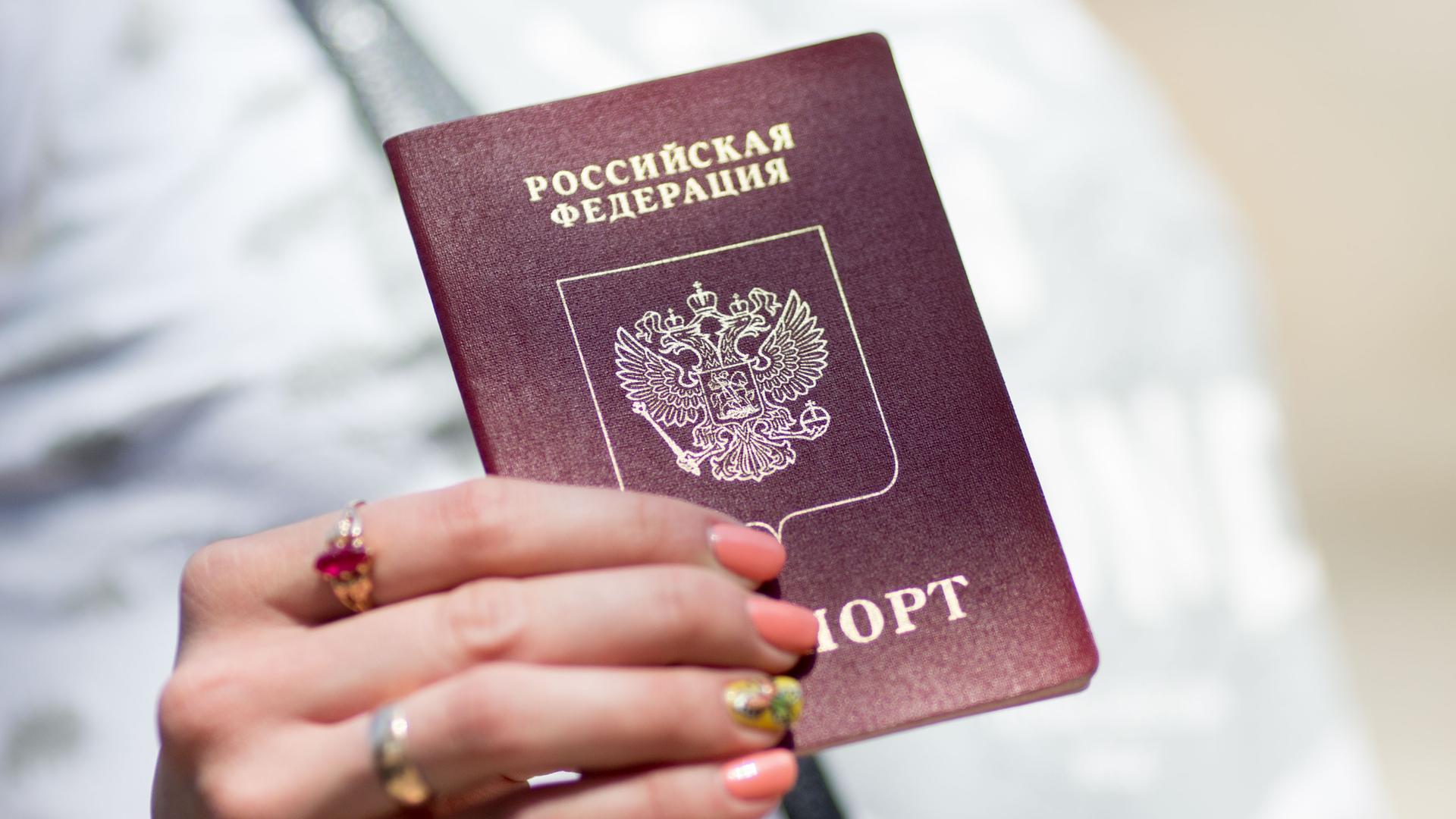 Eine Frau hält ihren russischen Reisepass in den Händen. Eine Frau hält ihren russischen Reisepass in den Händen.