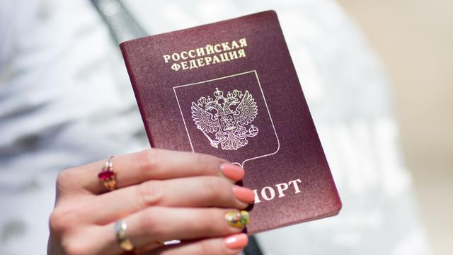 Eine Frau hält ihren russischen Reisepass in den Händen. 