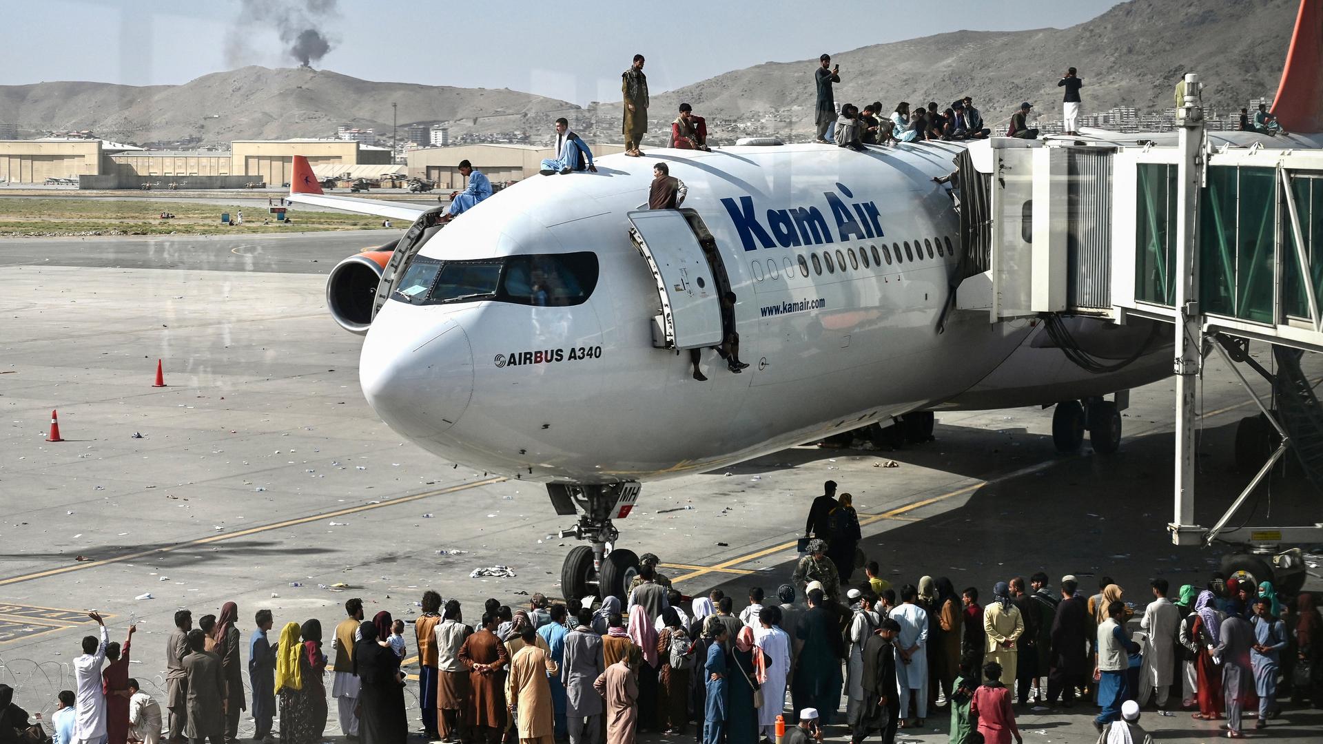 Afghanische Menschen klettern auf ein Flugzeug auf dem Flughafen in Kabul im August 2021. Sie versuchen verzweifelt zu fliehen, weil die Taliban die Macht übernommen haben. Afghanische Menschen klettern auf ein Flugzeug auf dem Flughafen in Kabul im August 2021. Sie versuchen verzweifelt zu fliehen, weil die Taliban die Macht übernommen haben.