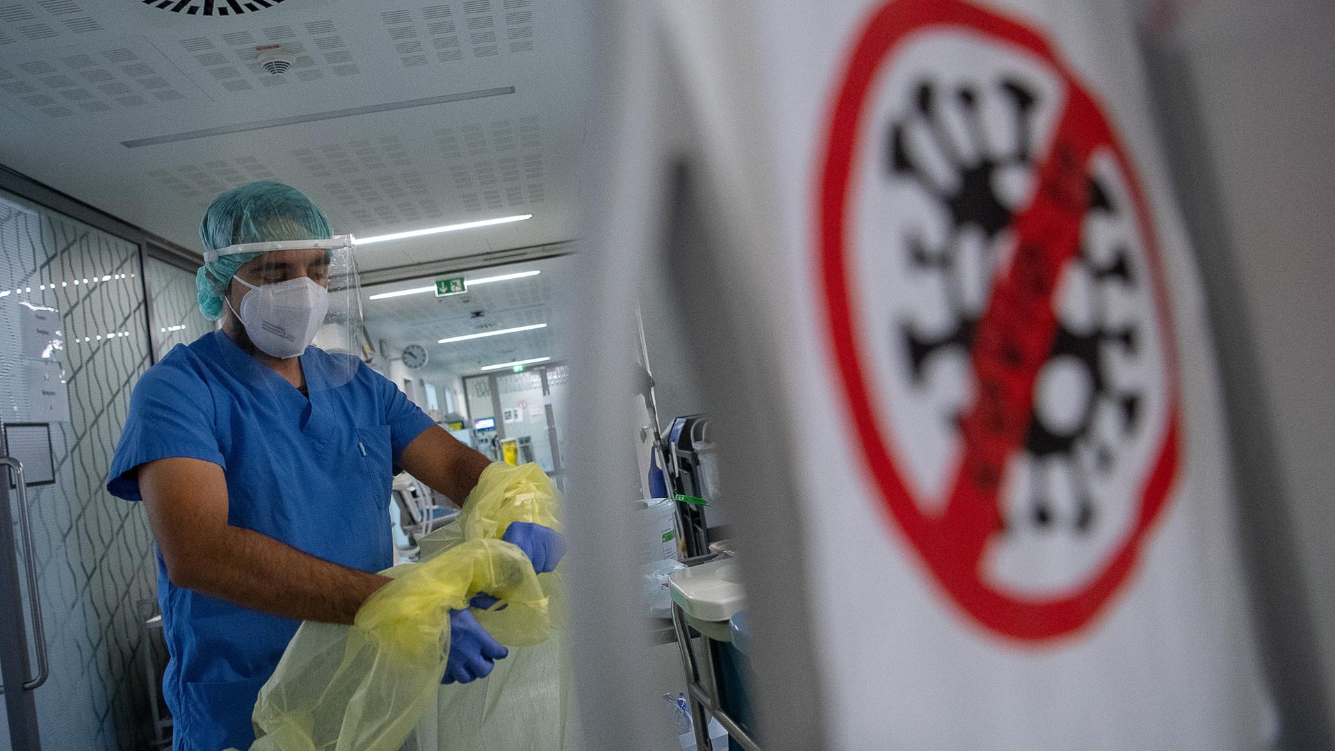 Ein Pfleger zieht sich beim Verlassen der Intensivstation für Corona-Patienten in einem Krankenhaus seinen Schutzkittel aus. Ein Pfleger zieht sich beim Verlassen der Intensivstation für Corona-Patienten in einem Krankenhaus seinen Schutzkittel aus.
