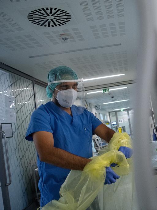 Ein Pfleger zieht sich beim Verlassen der Intensivstation für Corona-Patienten in einem Krankenhaus seinen Schutzkittel aus.