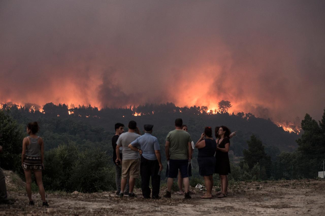 Menschen in Portugal beobachten aus der Ferne einen Waldbrand.