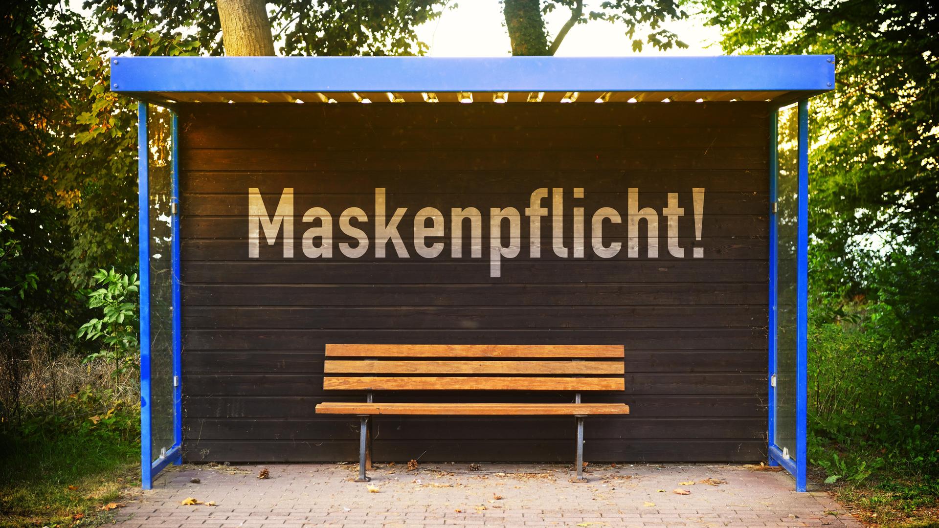 An einer Bushaltestelle prangt die Aufschrift "Maskenpflicht". An einer Bushaltestelle prangt die Aufschrift "Maskenpflicht".