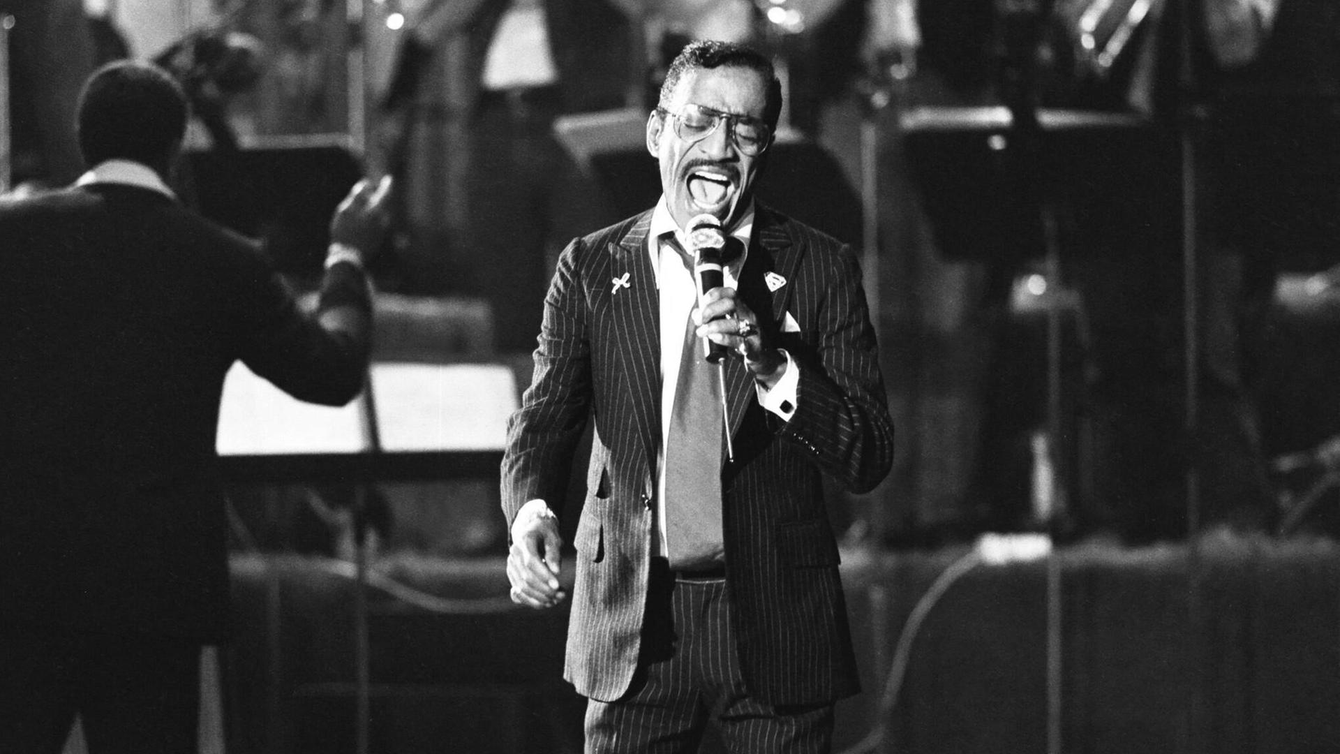 Sammy Davis Jr. singt mit einer Big Band im Hintergrund, 1982. Sammy Davis Jr. singt mit einer Big Band im Hintergrund, 1982.