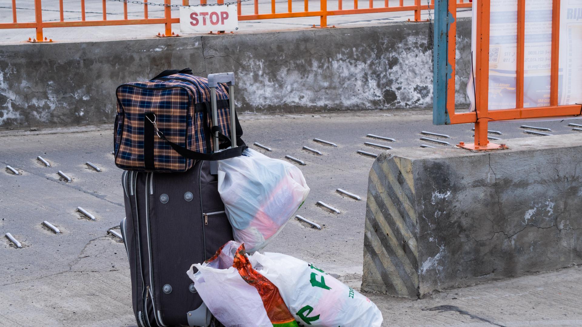 Reisetaschen und Koffer von einer Frau mit ihrem Kind stehen neben einem Fähranleger. Reisetaschen und Koffer von einer Frau mit ihrem Kind stehen neben einem Fähranleger.