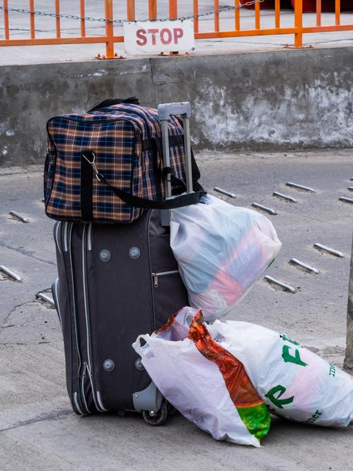 Reisetaschen und Koffer von einer Frau mit ihrem Kind stehen neben einem Fähranleger.