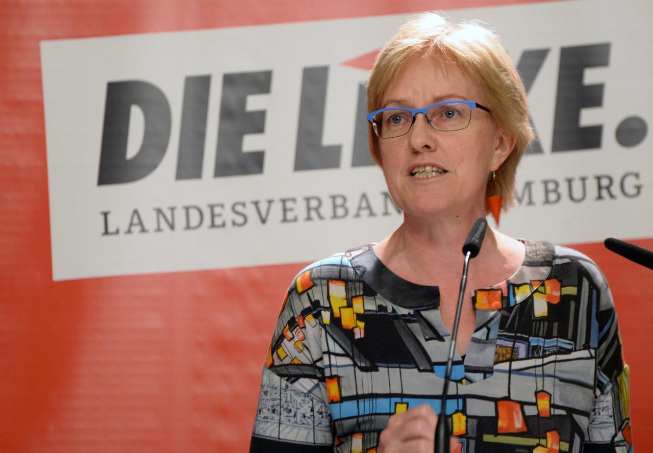 Heike Sudmann steht am Rednerpult, im Hintergrund ist das Logo der Partei "Die Linke" zu sehen: Sie trägt die Haare kurz, hat eine Brille und eine bunte Bluse. Heike Sudmann steht am Rednerpult, im Hintergrund ist das Logo der Partei "Die Linke" zu sehen: Sie trägt die Haare kurz, hat eine Brille und eine bunte Bluse.