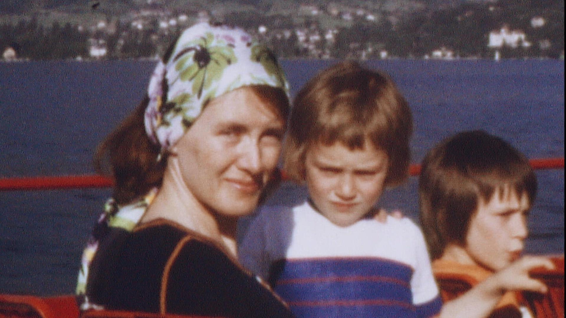 Alte Aufnahme von Annie Ernaux, die als junge Frau ein geblümtes Kopftuch trägt und mit zwei Kindern auf dem Oberdeck eines Ausflugsdampfers sitzt. Alte Aufnahme von Annie Ernaux, die als junge Frau ein geblümtes Kopftuch trägt und mit zwei Kindern auf dem Oberdeck eines Ausflugsdampfers sitzt.