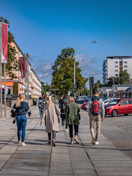 Passanten gehen an einem sonnigen Tag am Friedrich Wolf Theater in Eisenhüttenstadt vorbei.