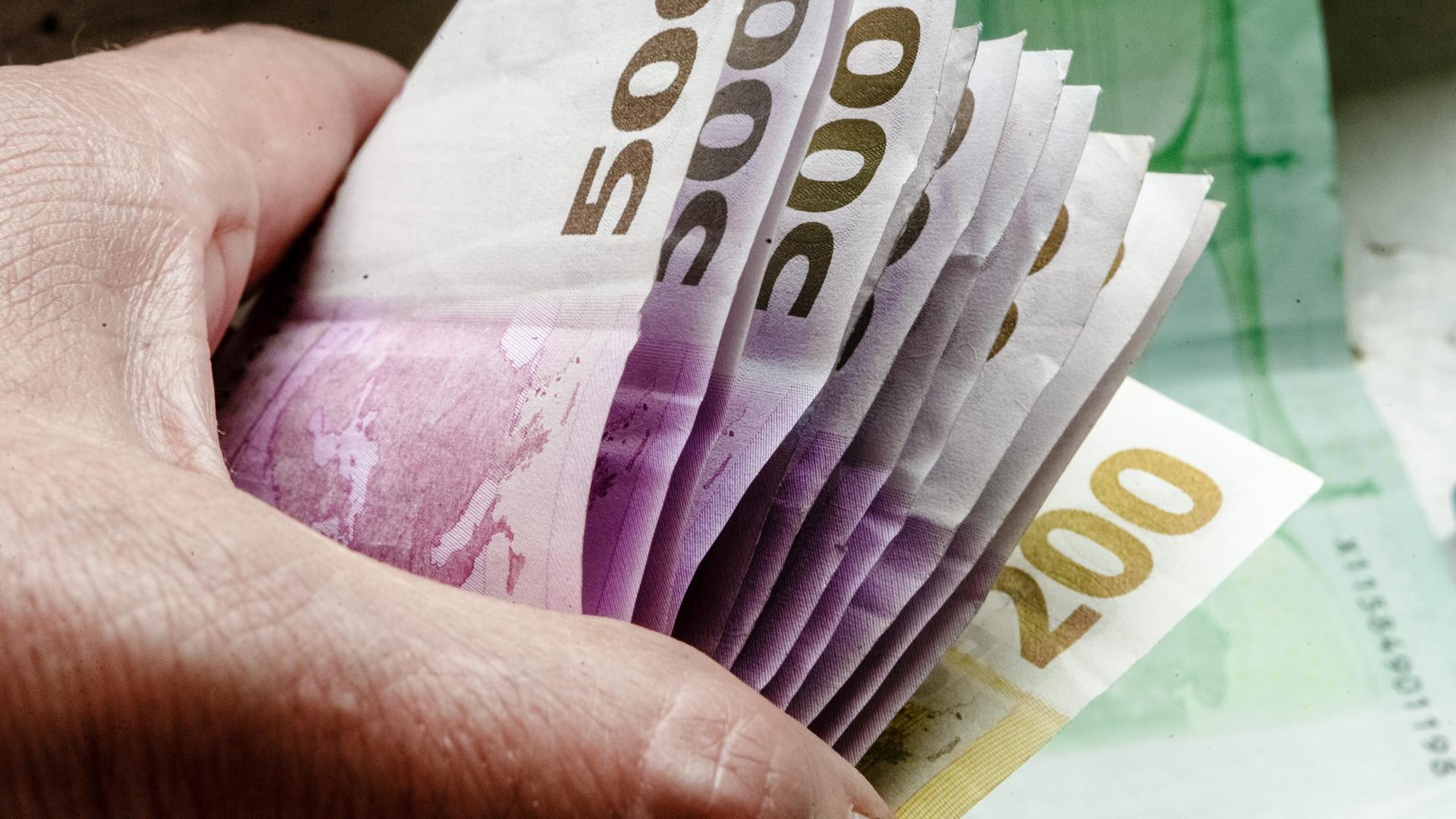 Eine Hand hält mehrere tausend Euro in 500-Euro-Scheinen. 