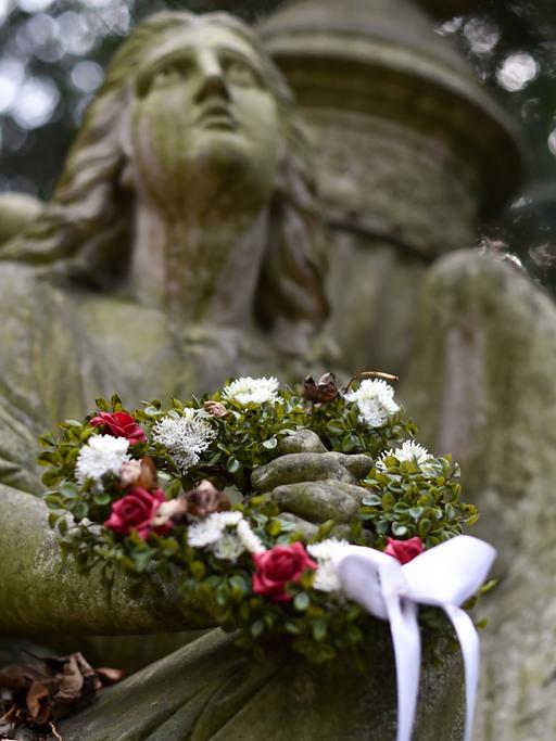 Ein Trauerengel mit Blumenkranz auf dem Hauptfriedhof in Frankfurt am Main.
