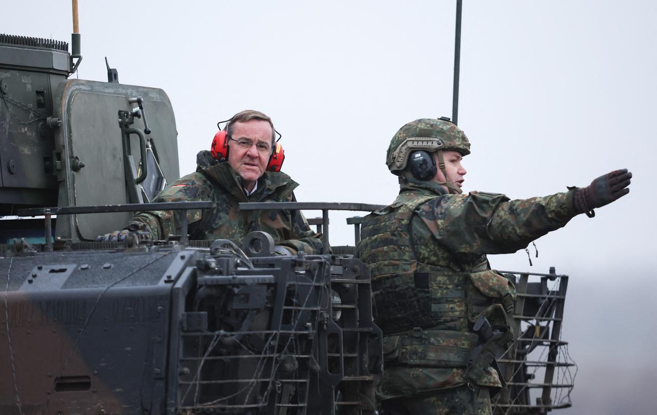Bundesverteidigungsminister Pistorius sitzt mit Ohrschützern auf einem Panzer. Ein Soldat erklärt ihm etwas. Bundesverteidigungsminister Pistorius sitzt mit Ohrschützern auf einem Panzer. Ein Soldat erklärt ihm etwas.