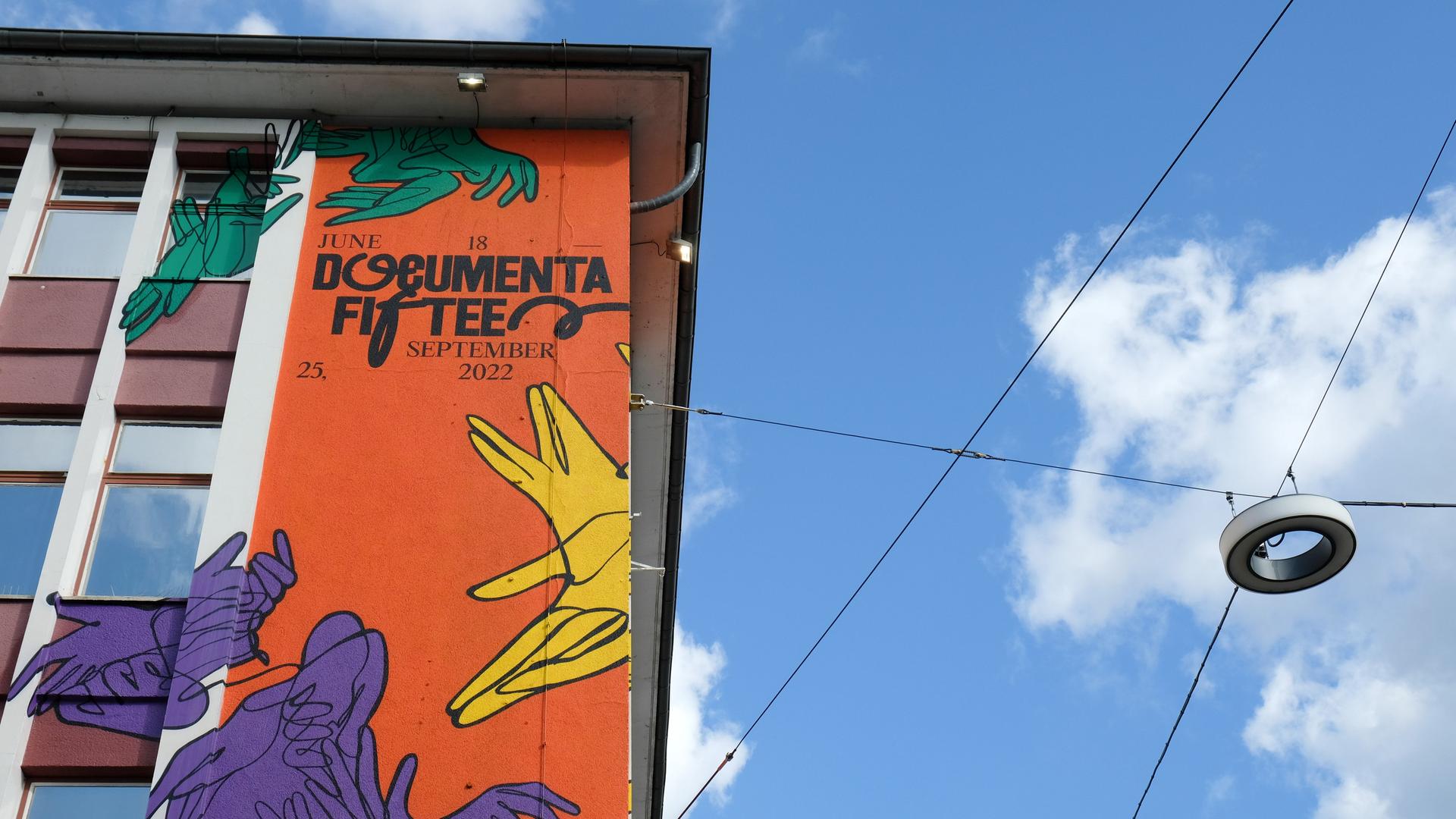 Der Schriftzug "documenta fifteen" und das Logo vom indonesischen Kuratorenkollektiv Ruangrupa prangt an der Fassade eines ehemaligen Sportgeschäftes in der Kasseler Innenstadt. Der Schriftzug "documenta fifteen" und das Logo vom indonesischen Kuratorenkollektiv Ruangrupa prangt an der Fassade eines ehemaligen Sportgeschäftes in der Kasseler Innenstadt.