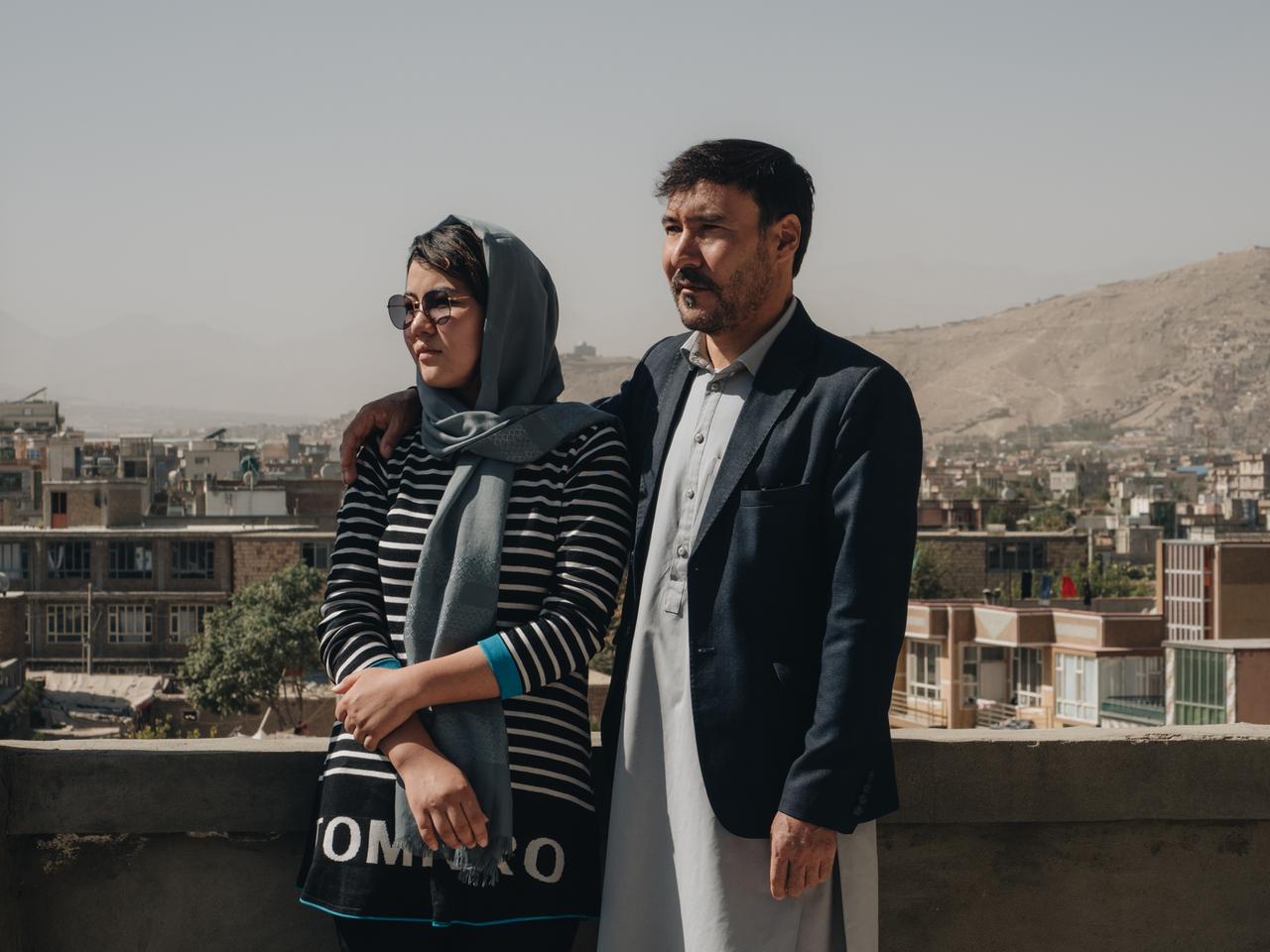 Ein Mann und eine Frau sehen auf einer Dachterasse, im Hintergrund eine Stadt: Muhammad Arif und seiner Tochter Mina in Kabul. 