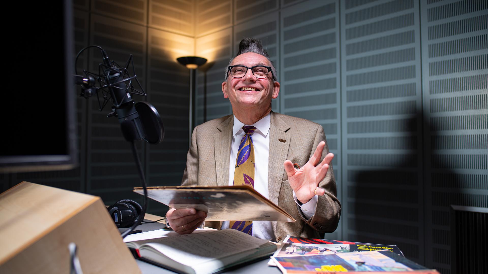 Moderator Götz Alsmann sitzt im WDR-Tonstudio in Münster vor dem Mikrofon und hält ein altes Plattencover in der Hand. Moderator Götz Alsmann sitzt im WDR-Tonstudio in Münster vor dem Mikrofon und hält ein altes Plattencover in der Hand.