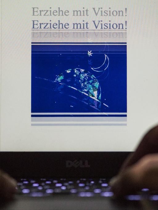 Nahaufnahme von zwei männlichen Händen an einem Laptop. Auf dem beleuchteten Display steht die Aufschrift "Erziehe mit Vision!" doppelt untereinander.