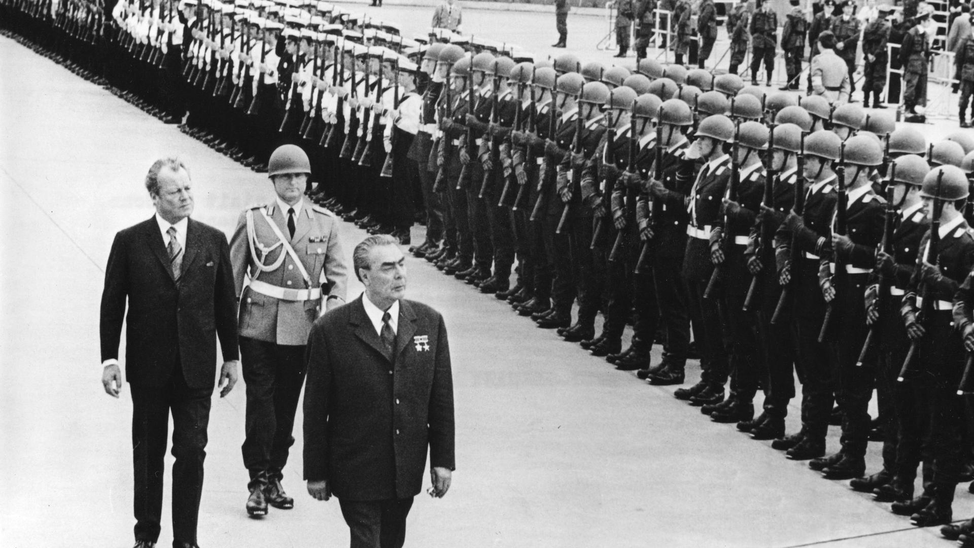 Willy Brandt (l.) und Leonid Breschnew. Zwei ältere Männer laufen eine Militärparade ab. Willy Brandt (l.) und Leonid Breschnew. Zwei ältere Männer laufen eine Militärparade ab.